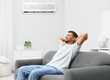 © New Africa - Happy man resting on sofa in room with air conditioner