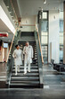 © Westend61 - Doctor and nurse walking and talking on staircase in clinic