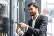 © Liubomir - Indian businessman scanning smartphone at office entrance to unlock door with nfc contactless access, showcasing secure, modern mobile authentication for corporate building access control