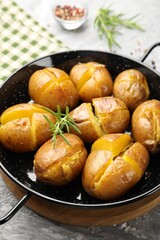 Wall Mural - Tasty baked potatoes with rosemary served on light grey table, closeup