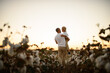 © Mariia Andreeva - Father and son wearing white t-shirts standing together in a cotton field in a rural village on a sunny day. Simple, peaceful family moment symbolizing love and connection.