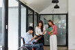 © David - Group shot of diverse business people, disabled asian man on wheelchair chatting with colleagues together at meeting room at office