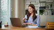 © matinee - Smiling businesswoman having a video conference call at her desk in a modern office.