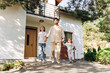 © Maria Vitkovska - Happy family, positive father and little daughters walking out of their modern house on sunny day