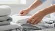 © Enigma - Hands neatly folding fresh clean white towels on a bed for home organization, laundry hygiene, and minimal lifestyle concept with focus on order and cleanliness