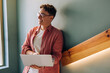 © (JLco) Julia Amaral - Smiling man using a laptop while leaning on a staircase indoors