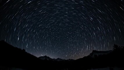 Wall Mural - dazzling stars rotate and streak across the inky black night sky above a silhouetted landscape in an