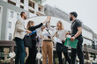 © qunica.com - A group of business professionals gathers outdoors, celebrating their success with enthusiasm and teamwork.