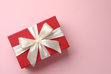 Wall Mural - Beautiful gift box with bow on pink background, top view. Space for text
