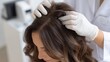 © dmmarychev - Dermatologist in gloves examining a woman's scalp and hair for diagnosis