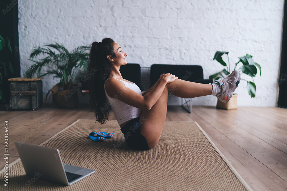 Virtual strength session as woman stretches into boat pose with raised ...
