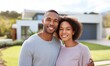 © Luiri Art - Smiling black couple standing together in front of new modern house on sunny day with green lawn and blue sky, concept of family happiness, real estate ownership and future home