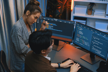 IT developers discussing with point to intelligent website development coder system running data online on pc of two screens with information technology at neon light room at modern office. Infobahn.