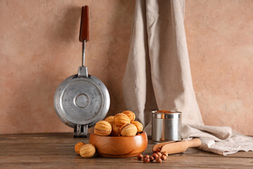 Wall Mural - Bowl with tasty walnut shaped cookies, boiled condensed milk and hazelnuts on wooden table