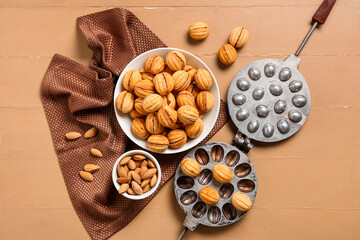 Wall Mural - Bowl with tasty walnut shaped cookies, almonds and baking form on beige wooden table