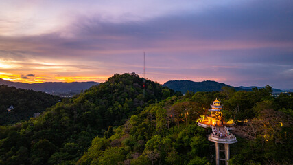 Wall Mural - Aerial view of A radiant sunset fills the sky with golden and orange hues above Khao Rang viewpoint,  highlighting the natural contours of the hills and the quiet charm of the urban landscape below.