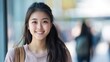 © sambath - A young woman with long hair smiling in a busy city environment.