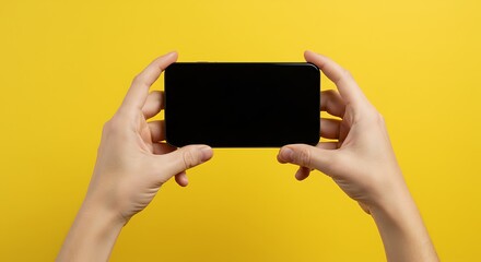 Modern hands holding a sleek smartphone with black screen against vibrant yellow background perfect for app marketing or mobile tech promo