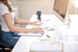 © bongkarn - Close up of a woman office worker's hands holding pen on clipboard and typing on computer keyboard.
