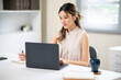 © bongkarn - Smart woman office worker holding pen and looking at laptop on white table in office.