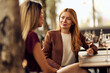 © bnenin - Two Women Enjoying a Conversation at an Outdoor Cafe With Drinks