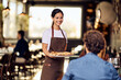 © bnenin - Cheerful Waitress Serving Pizza to Customers in a Restaurant Setting