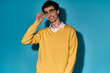 © Bliss - Handsome young man showcases stylish yellow sweater against bright blue backdrop