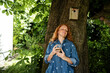 © Westend61 - Person relaxing outdoors in garden leaning on tree with drink