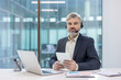© Liubomir - Serious mature businessman working at a call center, wearing a headset and holding a tablet, providing customer support or telemarketing services from a modern office desk