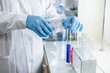 © NastyaPhoto - Scientist pouring liquid on test tube at laboratory. Attentive person wearing protective uniform while doing chemical experiment in the laboratory.