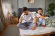 © Stockphotodirectors - A man and woman sit apart on their unmade bed, both looking troubled and lost in thought. Tension fills the air as they face away from each other, contemplating their relationship.