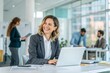 © TKN - Smiling businesswoman working on laptop in modern office