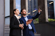 Coffee to go. Woman with paper cup of drink and her business partner during meeting outdoors