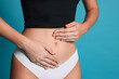 © New Africa - Young woman with flat belly on light blue background, closeup