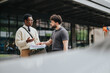 © qunica.com - Two colleagues engage in a serious conversation, reviewing documents in a professional setting outside.