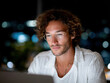 © AnaMadzar - Focused freelancer working late on laptop in city at night
