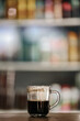 © Agus - Clear glass coffee cup on a wooden table with a blurred display refrigerator in the background