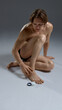 © master1305 - Shirtless male in black underwear applies cream to foot while sitting on floor. Concept of personal care advertising, skincare campaigns, wellness branding, and lifestyle health promotion.