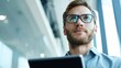 © Денис Рогожин - A young creative professional stands in a bright office with a tablet in his hands and a blank black screen.