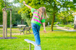 © kittyfly - Child walking balance beam in park, Little girl balancing outdoor equipment, green background, outdoor play, coordination exercise, kid in colorful sweater and jeans, active lifestyle, childhood fun