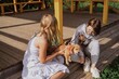 © looking2thesky - A young woman and her teenage daughter walk their playful puppy in a sunny garden, sharing a multigenerational moment of pet care and family bonding. Authentic, unaltered photography