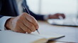 © stockbusters - Lawyer hands writing notebook at office closeup. Gray-haired businessman working