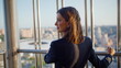 © stockbusters - Smiling brunette contemplating cityscape standing highrise building closeup.