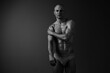 © SHOTPRIME STUDIO - Black and white image of a confident man showcasing his toned physique. The dramatic lighting accentuates his strong features, conveying strength and determination.