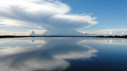 Wall Mural - dramatic clouds move gracefully across the sky, reflecting their dynamic patterns on a still body of