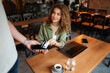 © Jelena - Young Woman Paying with Contactless Payment in a Cafe