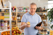 © JackF - Elderly man buyer chooses drink beer in grocery store