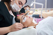 © Maria - Eyelash extension procedure with tweezers in beauty salon