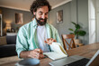 © Migma_Agency - Happy man writing notes while working from home
