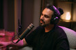 © Anna - Audio podcast recording studio. A young man sits at a table in front of a microphone, recording the release of an online audio show. The host is recording the show.
